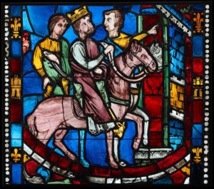 A stained glass panel showing three men on horseback entering a city, with one of them crowned.