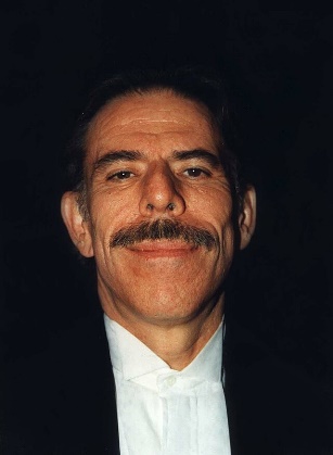 A person with a mustache smilingDescription automatically generated